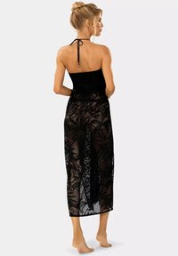 Czarny okrycie na szyję z dekoltem halter, wykonane z przezroczystej, wzorzystej siateczki, długości do kolan, z elastycznym pasem, odsłaniające nogi. Delikatny kwiatowy wzór.