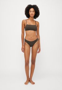 Brunt badedraktsett som har en enkel bralette-overdel med tynne stropper og lavtsittende underdel, laget av glatt stoff med et minimalistisk design.