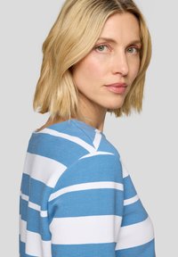 Gestreiftes Strickoberteil in Blau und Weiß mit gerippter Textur, das einen Bootsausschnitt und einen entspannten Schnitt hat. Der Stoff wirkt weich und leicht.