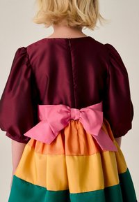 Farbenfrohes Kleid mit einem satinbewähten burgunderfarbenen Oberteil, Puffärmeln und einem ausgestellten Rock mit horizontalen Streifen in Grün, Gelb, Orange und Pink.