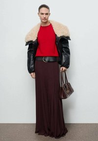 Czarna skórzana kurtka z sztucznym futrem, czerwony sweter, głęboki burgundowy maxi spódnica, czarny pasek i brązowa torebka. Gładkie faktury, swobodny design.