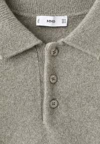 Polo in maglia grigia con colletto classico, patta con tre bottoni e una texture morbida. L'etichetta mostra il nome del marchio MNG.