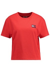 T-shirt in cotone rosso con scollo rotondo e maniche corte. Presenta una piccola etichetta con logo blu e bianco nell'area del petto sinistro.