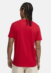 Rød kortærmet t-shirt lavet af bomuld, med rund hals og en glat tekstur. Synlige fletninger og ensfarvet bagside.