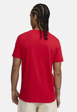 Red short-sleeve t-shirt made of cotton, featuring a crew neck and a smooth texture. Visible braided hair and plain back design.