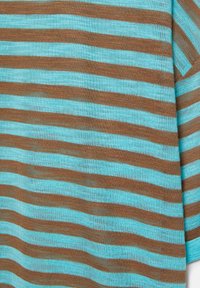 Gros plan d'un tissu avec des rayures horizontales turquoise et marron sur une surface textile tricotée.