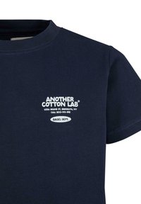 Camiseta de algodón navy con cuello redondo. Presenta texto impreso en blanco y un gráfico que resalta "Bagel Dept." en el frente.