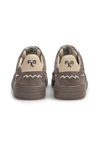 Une paire de baskets en suede marron avec des languettes de talon crème, un logo "FxB" noir, des coutures en zigzag et "Floris van Bommel" embossé sur les semelles.