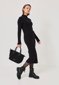 Vestito a maglia a coste nero con maniche lunghe, lunghezza al ginocchio, abbinato a una borsa nera texturizzata e stivali combat neri con lacci.