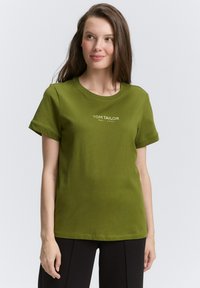 T-shirt en coton vert olive avec un col rond et des manches courtes, portant l'inscription "TOM TAILOR EST. 1962" imprimée en blanc sur le devant.