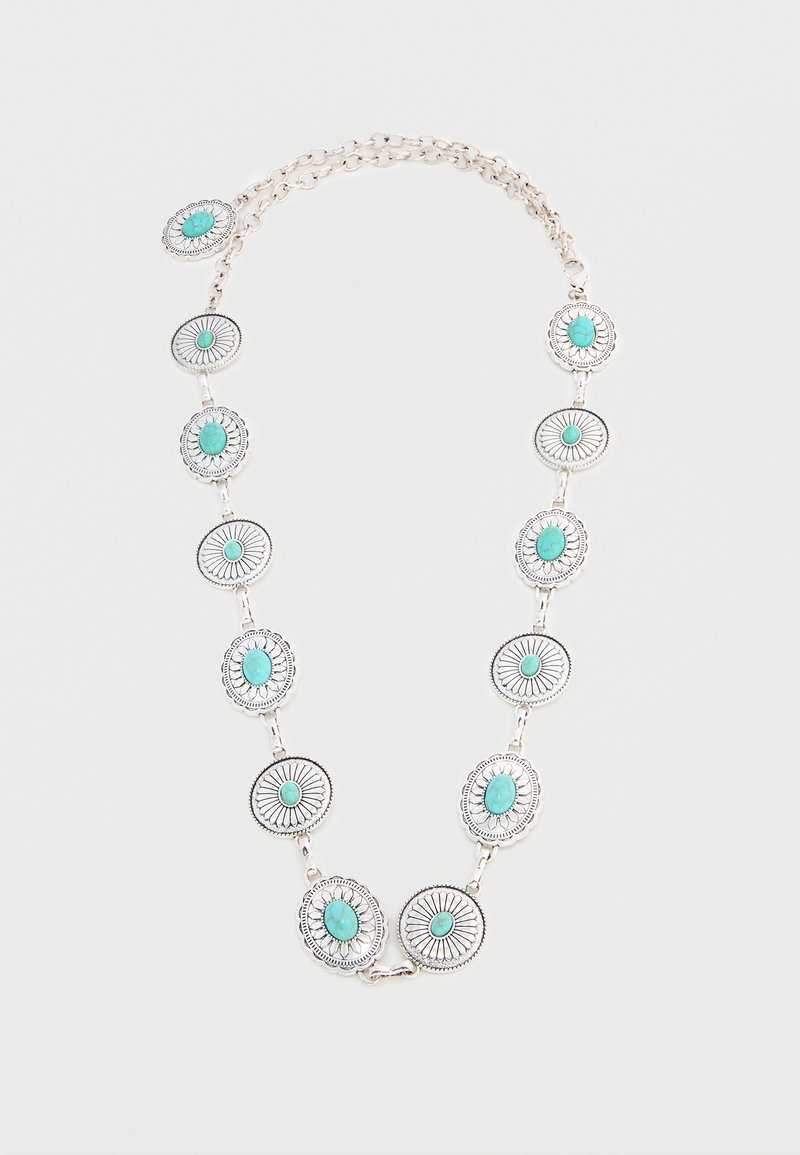 Collier en chaîne argentée avec dix pierres turquoises ovales serties dans des montures en métal détaillées au motif de rayons de soleil, espacées uniformément le long de la chaîne.