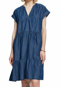 Denim dress featuring short sleeves, a V-neckline, and tiered ruffle skirt. The fabric is a medium blue with a textured finish.