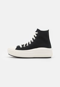 Czarne trampki typu high-top z płótna, z białymi oczkami i sznurówkami, cechujące się kremowym czubkiem z gumy oraz grubą białą podeszwą.
