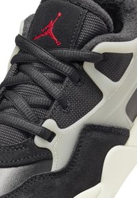 Sneakers noirs en matériaux synthétiques, avec un dessus en maille et des accents en suédine grise. Comprend un logo rouge bien visible et une semelle épaisse et texturée.
