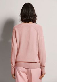 Helles rosa Sweatshirt aus weichem Strickstoff. Verfügt über einen runden Ausschnitt, lange Ärmel, gerippte Bündchen und eine lockere Passform.