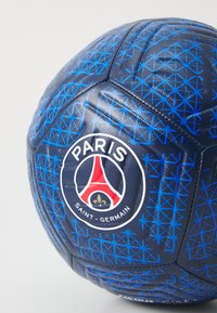 Blå fodbold med tekstureret overflade, geometrisk blå mønster, og et rundt logo med Eiffeltårnet og "Paris Saint-Germain."