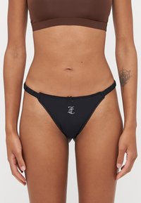 Bas de bikini noir avec dentelle, doté d'un petit nœud et d'un détail en strass monogramme à l'avant. Texture de tissu lisse.
