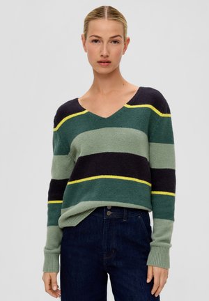 Gestreifter Pullover in Grün, Marineblau und Gelb. Mit V-Ausschnitt, gerippten Bündchen und weicher Textur. Kombiniert mit dunklen Jeans.