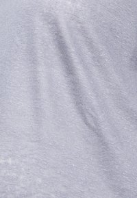 Tecido de malha azul claro com uma textura suave, exibindo variações subtis na tonalidade e uma trama lisa e uniforme. Sem padrões ou acessórios distintos.