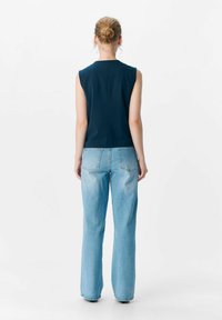 Haut sans manches bleu foncé à coupe droite, associé à un jean flare bleu clair avec un design de poche classique et un léger délavage.