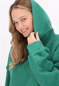 Fleece hætte sweatshirt i dyb grøn, med en struktureret overflade, ribbede manchetter og en hyggelig hætte. Blødt og behageligt design.