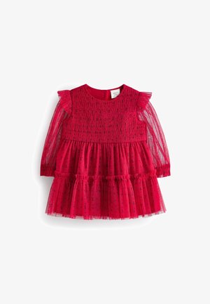 Czerwona sukienka z tiulu, z marszczonym gorsetem i długimi przezroczystymi rękawami. Posiada warstwowe falbanki i okrągły dekolt. Małe ozdobne wzory.