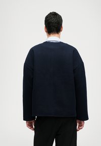 Mjukt tyg, marinblå oversized sweatshirt med rund halsringning, långa ärmar och rak fåll. Minimalistisk design.