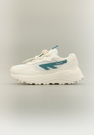 Baskets blanches de sport avec semelle épaisse, logo et accents turquoise, textures en mesh et daim, et fermeture à lacets sur un fond uni.