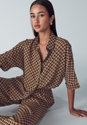 Bruine en zwart gemêleerde shirt met een geometrisch ontwerp, met een kraag en losse mouwen, gecombineerd met bijpassende losse broek.