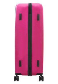 Hard-shell pink suitcase with a glossy finish, featuring a black zipper, side handles, and four multi-directional wheels for easy maneuverability.