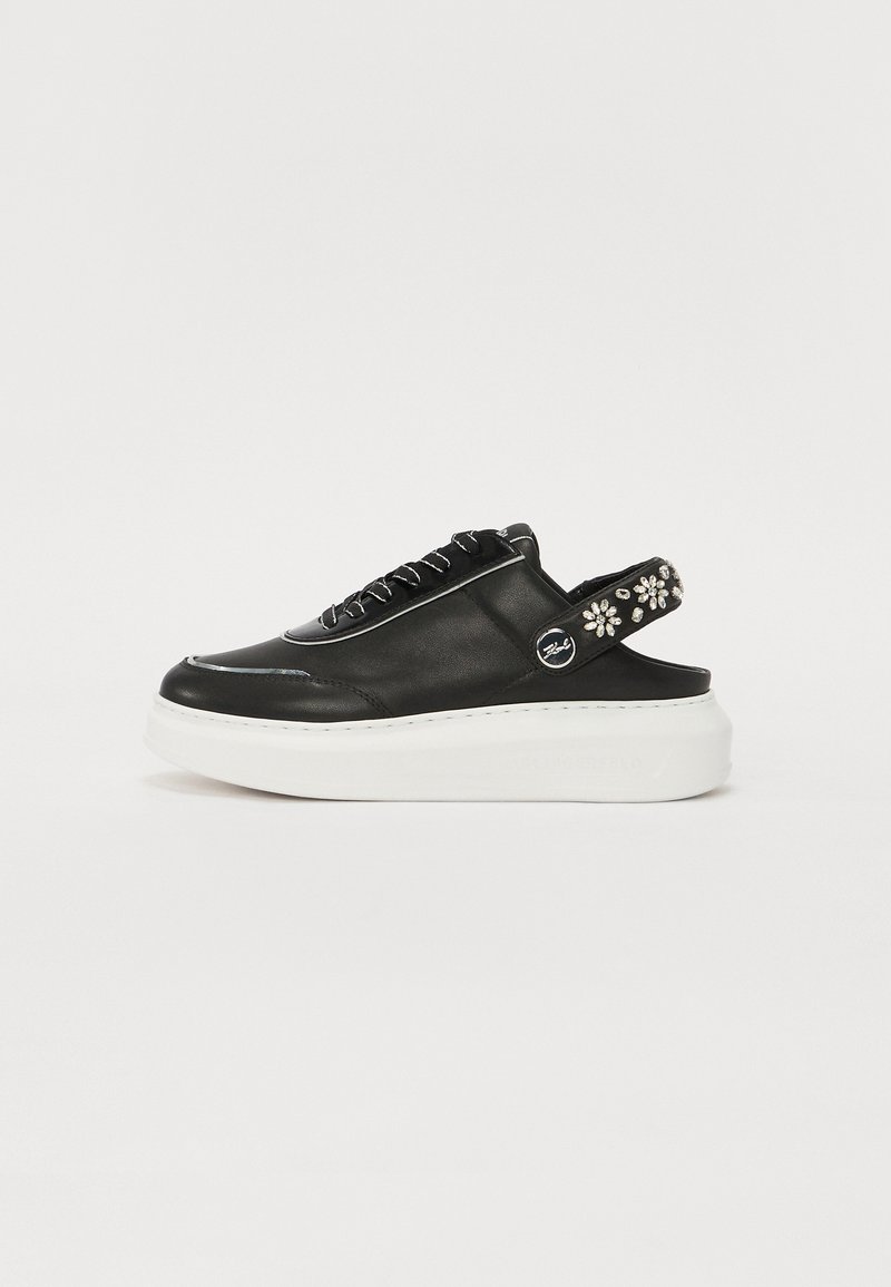 Sorte lær slip-on sko med en hvit plattformsåle. Har en snøring-design og dekorative blomsterdetaljer på bakre stropp.