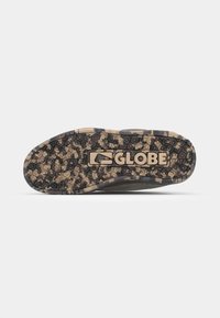 Sneaker outsole with a dark camouflage pattern, featuring textured rubber for grip and a prominent "GLOBE" logo etched in the center.