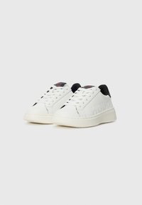 Hvite lavtopp sneakers med svarte hælalternativer, preget "HUGO"-merke på sidene, hvite lisser og logotag på tungen.