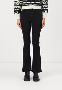 Melni platā kāja džinsi, izgatavoti no denima, izceļas ar klasisku piecu kabatu dizainu un pieguļošu jostasvietu. Kombinēti ar rakstainu džemperi un stilīgām melnām kurpēm.