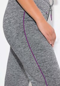 Graue Sporthosen aus strukturiertem Stoff mit einem kontrastierenden lila Seitenstreifen und einem elastischen Bund mit Kordelzug.