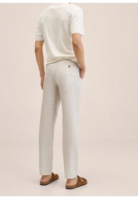 Jasnoszare lniane spodnie o prostym kroju, z tylną kieszenią i subtelnym guzikiem. W zestawieniu z kremowym topem z krótkim rękawem i brązowymi wsuwanymi butami.