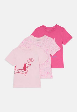 Tre t-skjorter: en lys rosa med hundegrafikk, en mønstret med forskjellige hundesilhuetter, og en solid lys rosa.