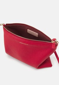 Rød læderpose med tekstureret finish, lynlås i gyldent metal og strop. Indvendig foret med mørkt stof, med en mærkeseddel.