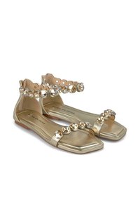 Gouden metallic platte sandalen met een doorzichtige band bezet met edelstenen over de voorkant en enkel voor extra detail, met een vierkante neusontwerp.
