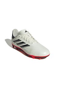 Botas de fútbol sintéticas blancas con rayas negras, suela roja de goma y cierre con cordones. Presenta una textura suave y un diseño curvado.