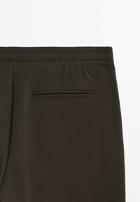Dunkelgrüne Jogginghosen aus weichem Stoff mit elastischem Taillenbund und einer kleinen Gesäßtasche mit genähtem Verschluss.