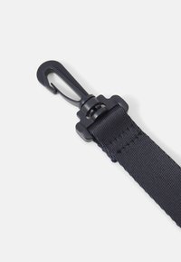 Sangle en nylon noir avec une surface texturée, dotée d'un crochet à pression en plastique pour l'attache et d'un fermoir robuste.