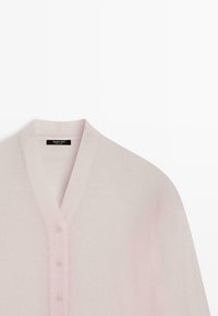 Cardigan rose clair en tissu doux, avec un col en V, cinq boutons sur le devant et des manches longues.