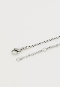 Zilveren metalen ketting met een kreeftsluitring en ronde schakels, die een gladde textuur en minimalistisch design toont.
