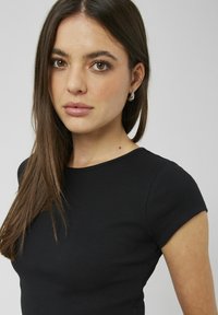 T-shirt noir à côtes avec des manches courtes et un col rond. Texture lisse avec une coupe ajustée, mettant en valeur le col et les manches.