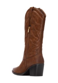 Botas de vaquero de cuero marrón con costuras decorativas, cremallera lateral y un tacón grueso negro. Presenta un caña alta y punta redonda.