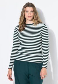 Top de manga larga a rayas en verde oscuro y blanco, textura acanalada, cuello redondo. Combinado con pantalones de pierna ancha en verde oscuro.