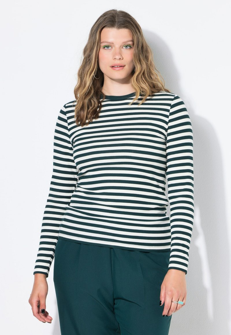 Top de manga larga a rayas en verde oscuro y blanco, textura acanalada, cuello redondo. Combinado con pantalones de pierna ancha en verde oscuro.