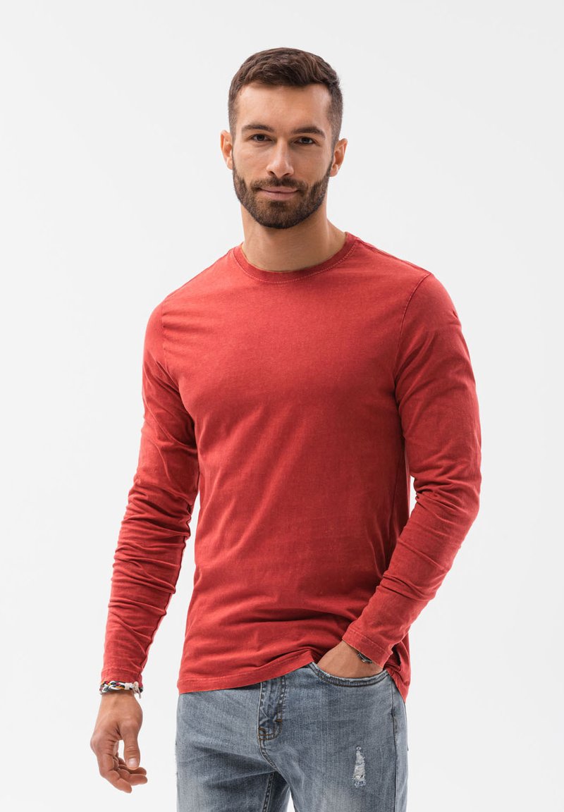 Rode langesleeve T-shirt met een ronde hals, gemaakt van zachte stof, met een slim fit en licht verwoeste blauwe jeans.