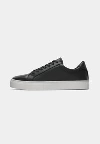 Black leather low-top sneakers with rounded toe, lace-up front, and white rubber sole. Smooth texture with minimalistic design elements.